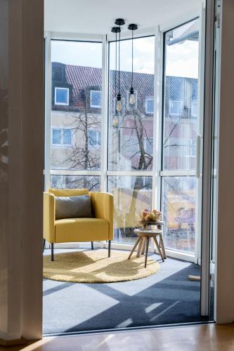 a living room with a yellow chair and a large window at Stadthotel Freilassing in Freilassing