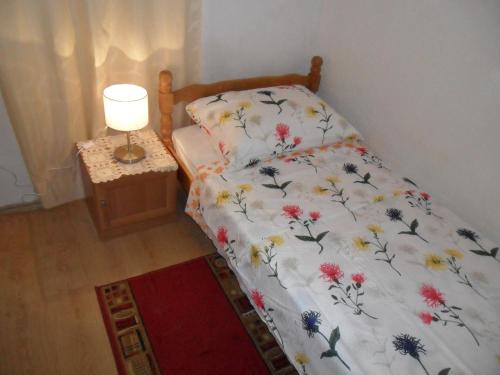 a bedroom with a bed with a floral bedspread and a lamp at Room Center Old Town in Dubrovnik