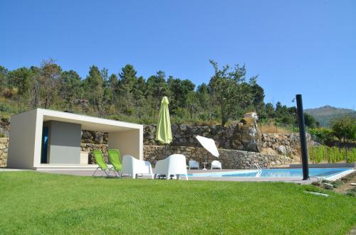 a backyard with a pool with chairs and an umbrella at Vald'arêgos - Douro in Resende
