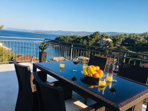 a table with a bowl of fruit and glasses of wine at Holiday Hvar in Vrbanj