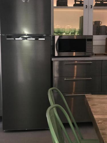 a kitchen with a stainless steel refrigerator and a microwave at HOSTEL ALAMEDA EXCLUSIVE HOUSE in Faro