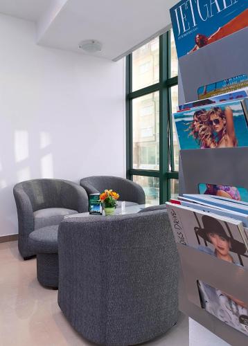 a living room with two chairs and a table and posters at Hotel Green Center Gili in Gostivar
