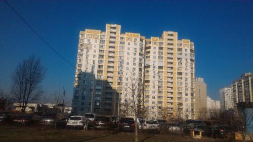 a tall building with cars parked in front of it at 1/10 вулиця Радунська in Kyiv
