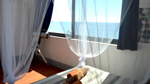 a bedroom with a window with a view of the ocean at Teocle Beach rooms in Giardini Naxos