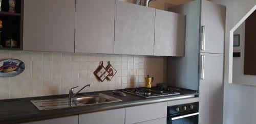 a kitchen with white cabinets and a sink and a stove at La Casa del Colibrì in Lecco