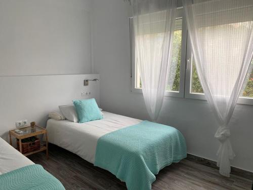 a white bedroom with a bed and two windows at El Rincón de Cristina in Torre de Benagalbón