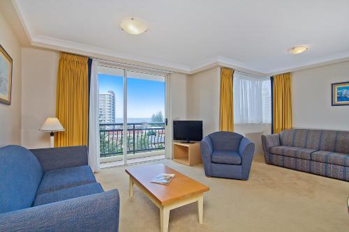 a living room with two blue couches and a television at Palazzo Colonnades in Gold Coast