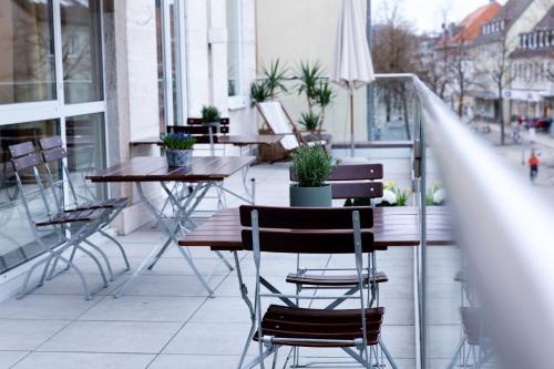 a table and chairs on a balcony with plants at Stadthotel Freilassing in Freilassing