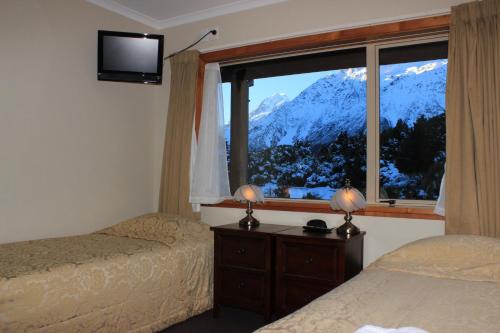 a bedroom with two beds and a window with a mountain view at Aoraki Mount Cook Alpine Lodge in Mount Cook Village