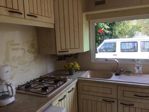 a kitchen with a stove and a sink and a window at Camping Le Canoë in Chaussin