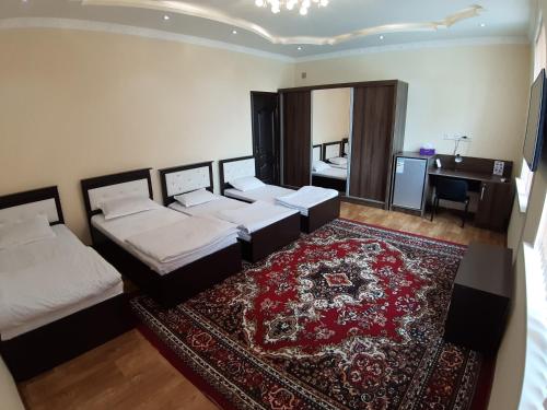 a bedroom with three beds and a rug and a desk at City Hostel Dushanbe in Dushanbe