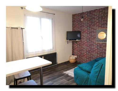 uma sala de estar com um sofá azul e uma parede de tijolos em BnBesak Besancon Micropolis em Besançon