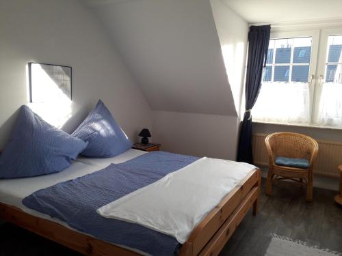 una camera da letto con un letto con cuscini blu e una sedia di Apartments Norddeicher Straße a Norden