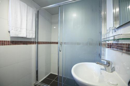 y baño con lavabo y ducha acristalada. en The Imperial Hotel, en Hong Kong