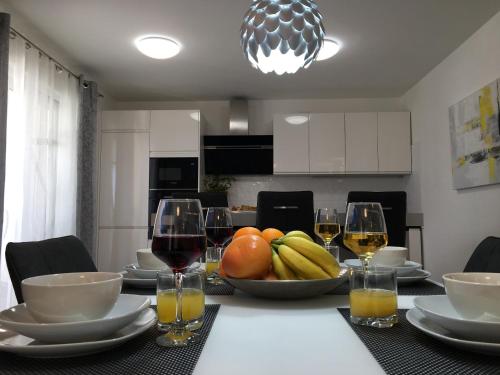 a table with a bowl of fruit and glasses of wine at Holiday Hvar in Vrbanj