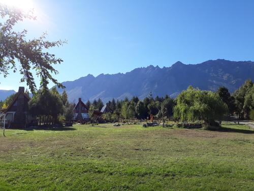 a field with houses and mountains in the background at Del Viejo Camino in El Bolsón