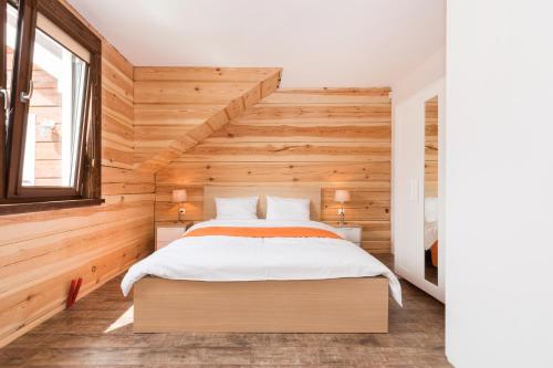 łóżko w pokoju z drewnianą ścianą w obiekcie Przy Rozlewisku w Sarbinowie