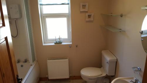 a bathroom with a white toilet and a window at Ocean Bay in Malin