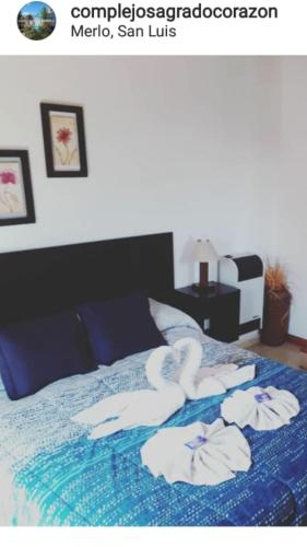 a bed with two swans towels on it at Complejo Sagrado Corazón in Merlo