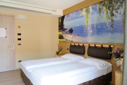 two beds in a room with a painting on the wall at Eco Hotel Bonapace in Nago-Torbole