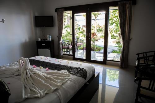 a bedroom with a bed and a sliding glass door at Kelapa Lovina Beach Villa in Lovina