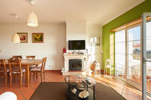 a living room with a table and a fireplace at Coral Villa in Ericeira