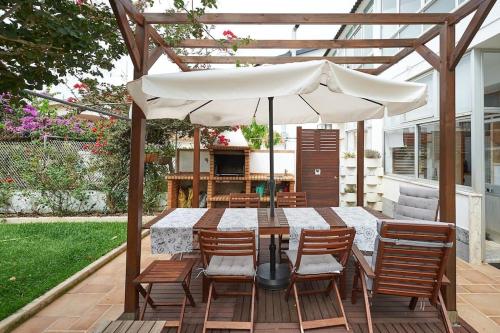 a patio with a table with chairs and an umbrella at Beija-Flor House in Ribamar