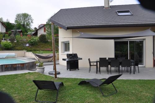un patio avec une table, des chaises et un parasol dans l'établissement Maison avec piscine 8 couchages entre Annecy et Aix les bains, à Rumilly