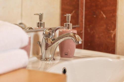 a bathroom sink with a faucet and a pink soapenser at Casa Vesna in Rovinj
