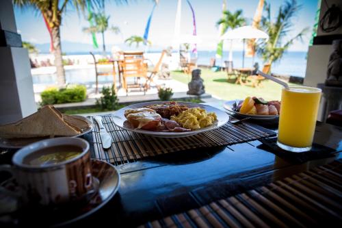 una mesa con platos de desayuno y un vaso de zumo de naranja en Kelapa Lovina Beach Villa, en Lovina