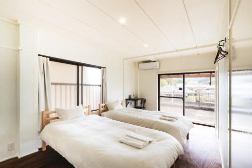 two beds in a room with a window at Hostel Marika -ホステルマリカ- in Nichinan