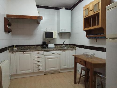 uma cozinha com armários brancos, um lavatório e uma mesa em Casa Rural San Blas em Sanjuanejo