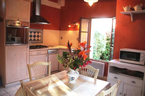 une cuisine avec une table avec un vase de fleurs dessus dans l'établissement Maison du cheval, à Concarneau