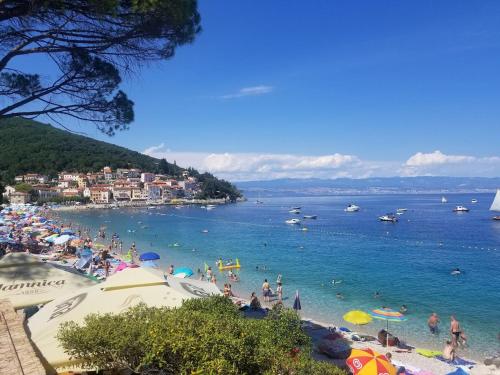 a group of people on a beach with umbrellas at Apartment Podini in Brseč