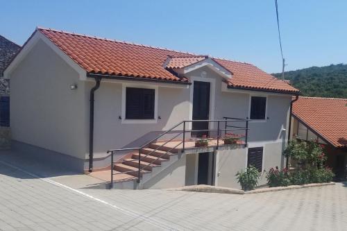 a white house with a staircase in front of it at Apartment Podini in Brseč