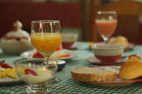 een tafel met twee glazen sinaasappelsap en brood bij Pousada Dona Felicidade in Cunha