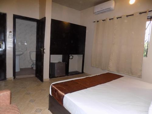 a bedroom with a bed and a bathroom with a window at Posh Apartments Business Hotel in Ikeja