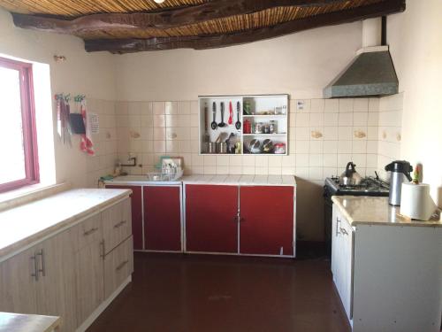 a kitchen with red cabinets and a white tiled wall at Refugio Don Natu in San Pedro de Atacama
