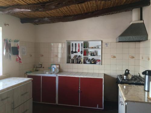 a kitchen with red cabinets and white tiled walls at Refugio Don Natu in San Pedro de Atacama