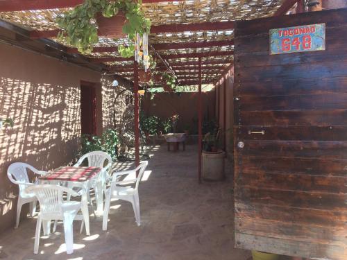 a patio with a table and chairs and a pergola at Refugio Don Natu in San Pedro de Atacama