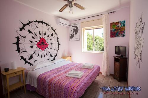 a bedroom with a bed with a flower on the wall at Etna Travellers B&B in Mascalucia