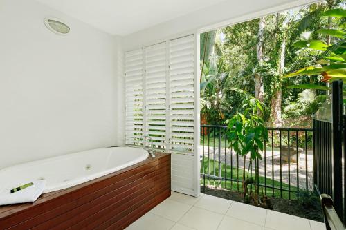 a bathroom with a tub and a large window at Peppers Beach Club & Spa in Palm Cove