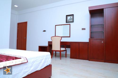 a bedroom with a bed and a desk and a table at RJ Mahaal Hotel in Kilinochchi