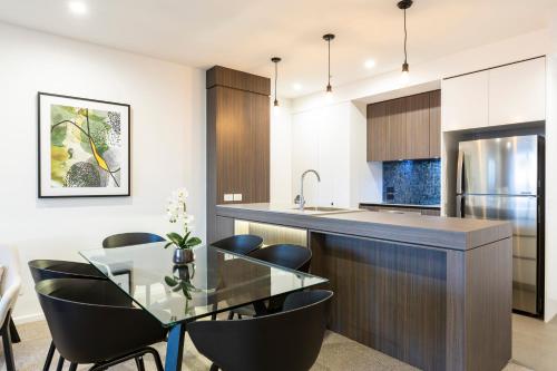 a kitchen with a glass table and black chairs at Qube Broadbeach in Gold Coast