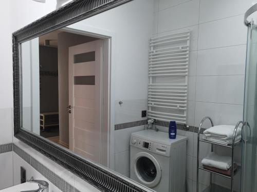 een badkamer met een spiegel en een wasmachine bij Apartament Południowy in Radom