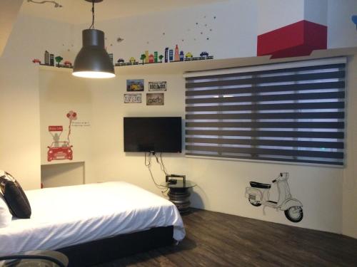 a bedroom with a bed and a tv and a scooter at Traveler Station R15 in Kaohsiung