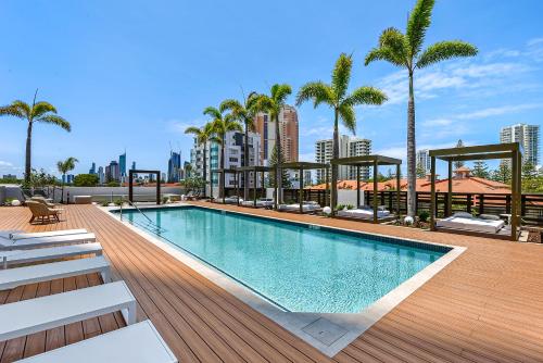 a swimming pool on top of a building with palm trees at Qube Broadbeach in Gold Coast