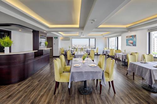 a dining room with tables and yellow chairs at Ocean Haven Hotel in Da Nang