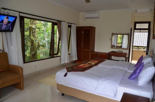 a bedroom with a large bed and a tv in it at Cempaka Belimbing Villa in Blimbing
