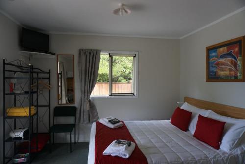a bedroom with a bed with red pillows and a window at Abel Tasman Haven in Marahau
